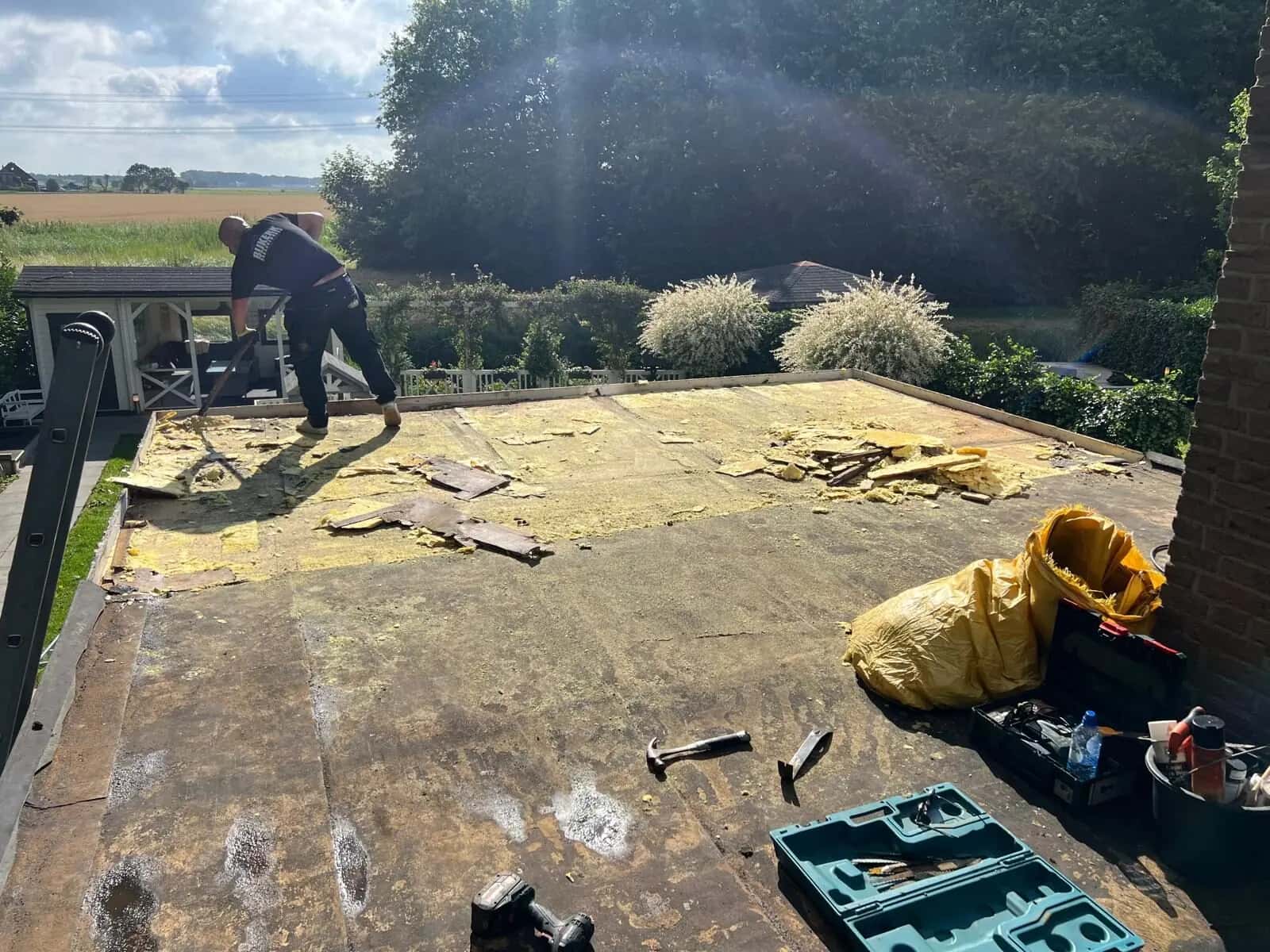 Dakdekker aan het werk bij het verwijderen van oude dakbedekking op een plat dak