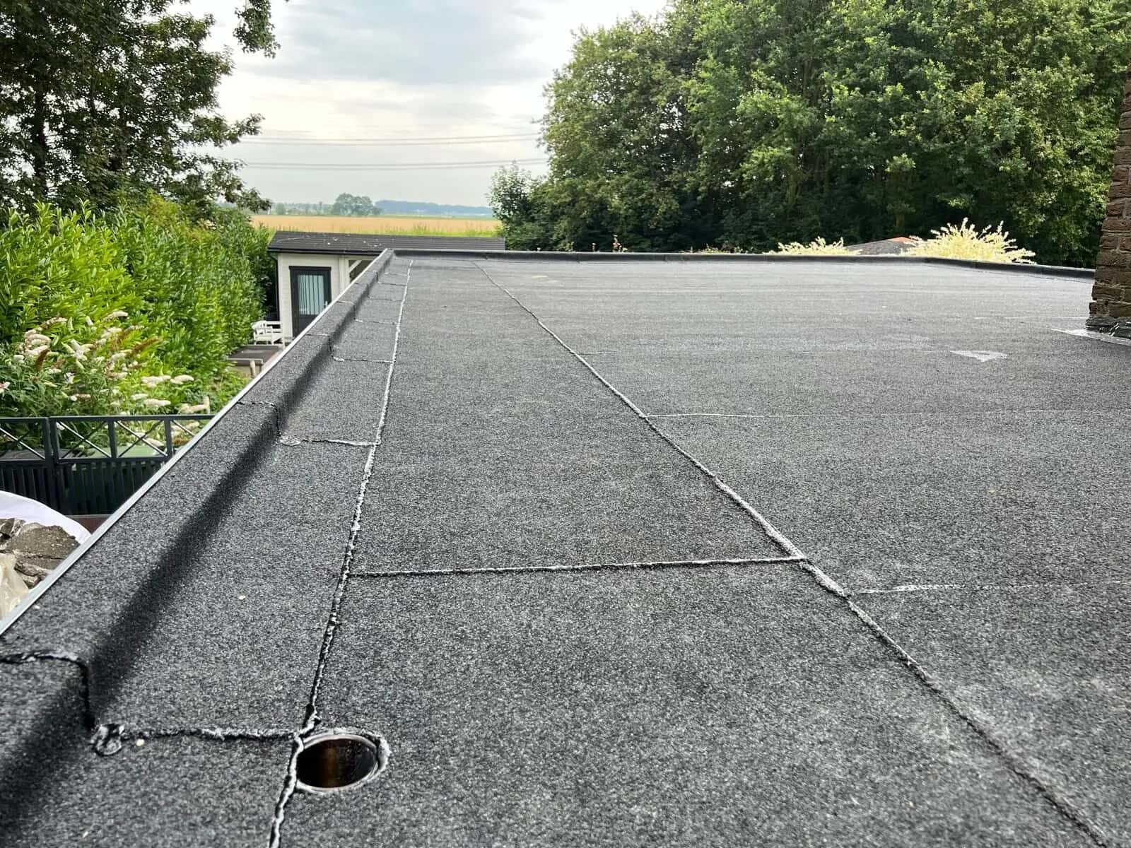 Groot plat dak met nieuwe donkergrijze dakbedekking en een dakafvoer