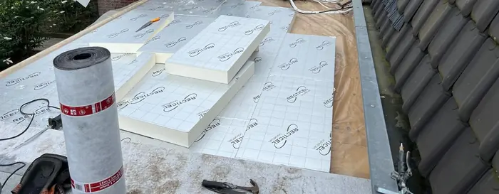 Isolatieplaten naast een rol dampremmende laag op het dak bij de dakpannen