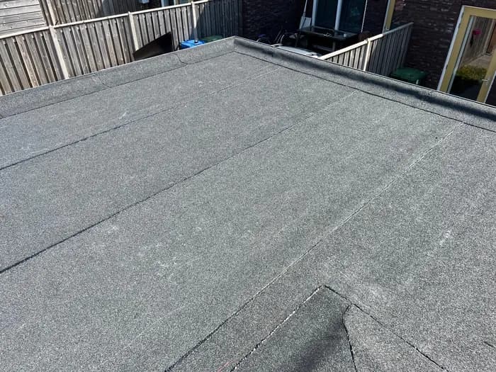 Nieuwe donkergrijze dakbedekking met afgewerkte opstand langs de dakrand