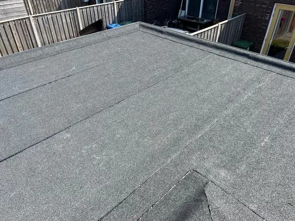 Na het werk: plat dak met nieuwe donkergrijze dakbedekking en afgewerkte randen