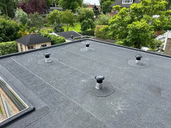 Na het werk: plat dak met nieuwe grijze dakbedekking en nieuwe ontluchtingen
