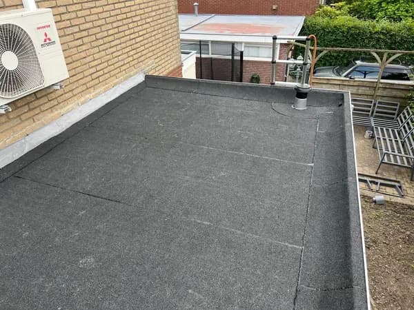 Na het werk: plat dak met nieuwe donkergrijze dakbedekking en afgewerkte dakranden