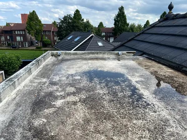 Vóór het werk: vervuild plat dak met plassen water naast een pannendak, Hendrik-Ido-Ambacht