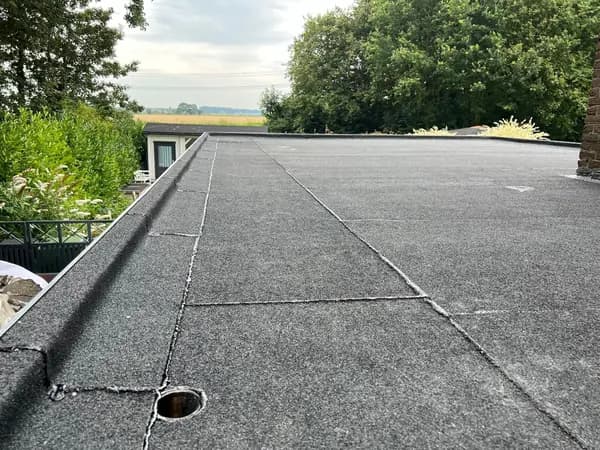 Na het werk: groot plat dak met nieuwe donkergrijze dakbedekking en dakafvoer, Maasdijk